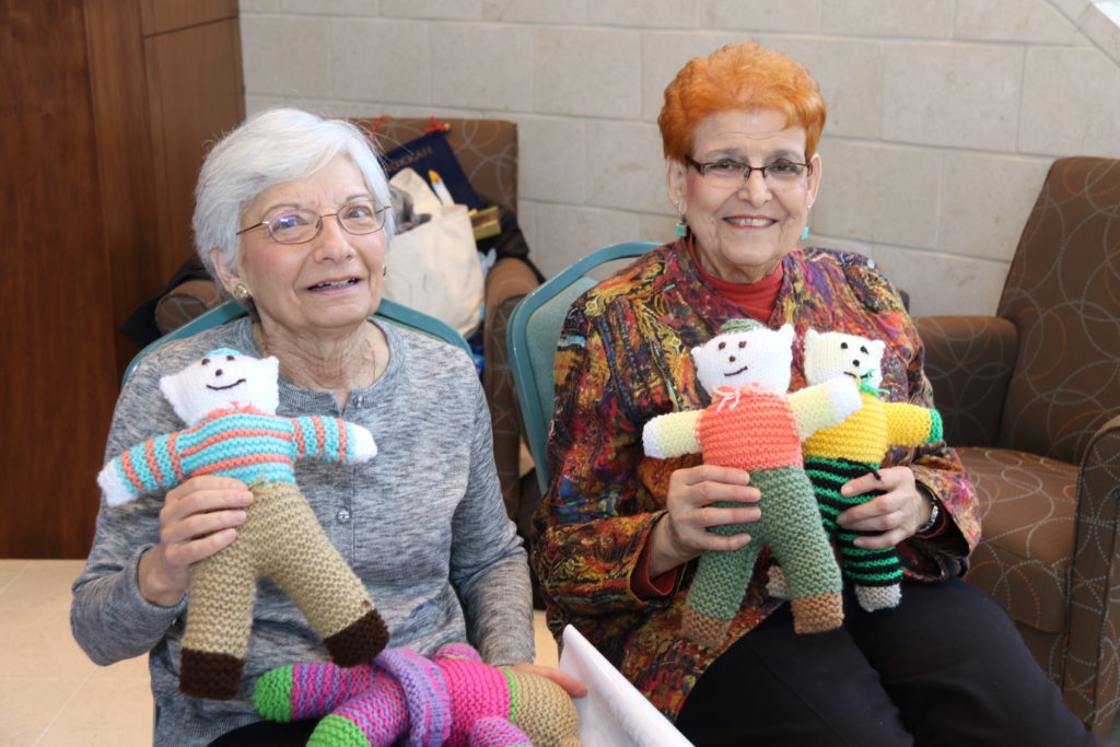 women holding knitted bears